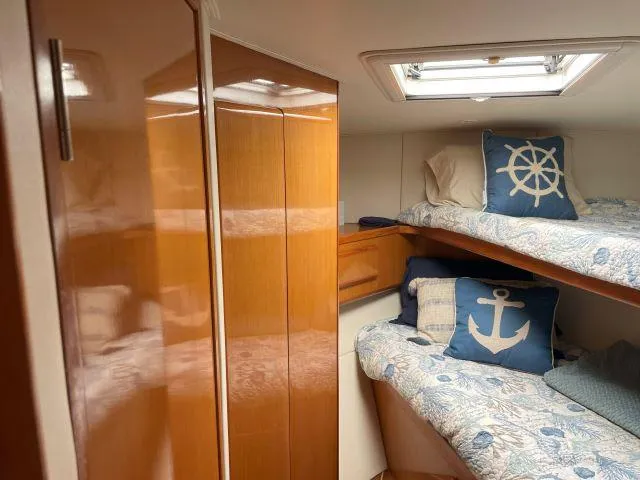 Slide: The Image of 1999 Viking 50 Convertible cabin with bunk beds, nautical-themed pillows, and wooden cabinetry. - 40