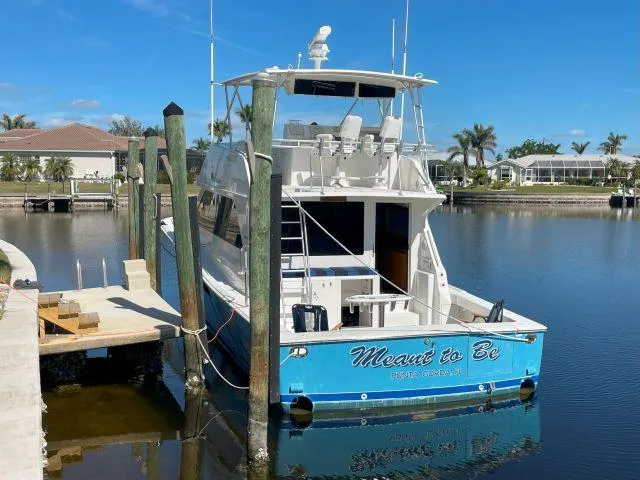 Slide: The Image of 1999 Viking 50 Convertible yacht docked, blue hull, sunny day, waterfront homes in background. - 5