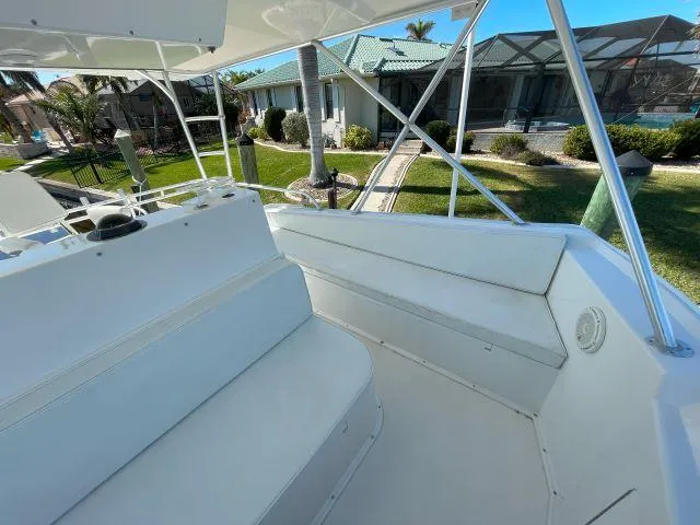 Slide: The Image of 1999 Viking 50 Convertible boat deck with seating, overlooking a landscaped yard. - 7