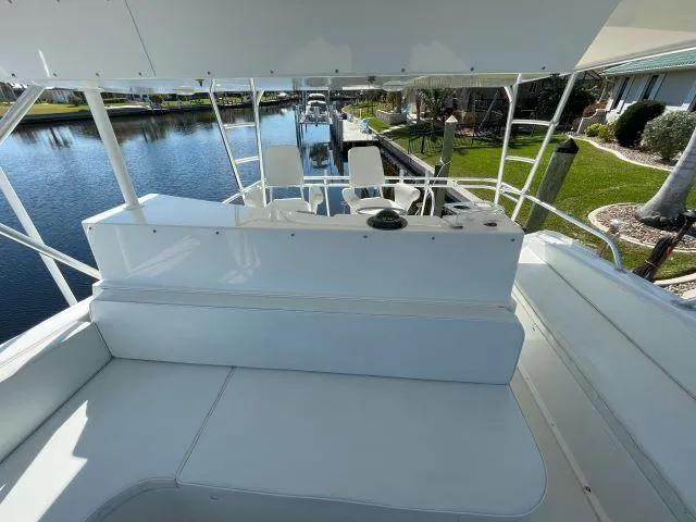 Slide: The Image of 1999 Viking 50 Convertible yacht interior with seating and helm, docked by a canal. - 9