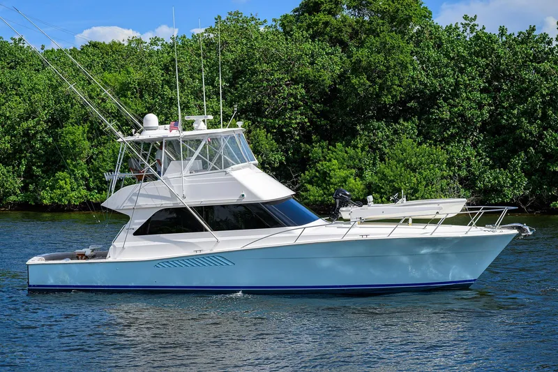 Slide: The Image of 2000 Viking 50 Convertible yacht cruising on a serene waterway with lush greenery. - 1
