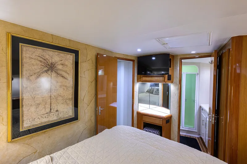 Slide: The Image of Interior of 2000 Viking 50 Convertible yacht bedroom with TV, artwork, and ensuite bathroom. - 18