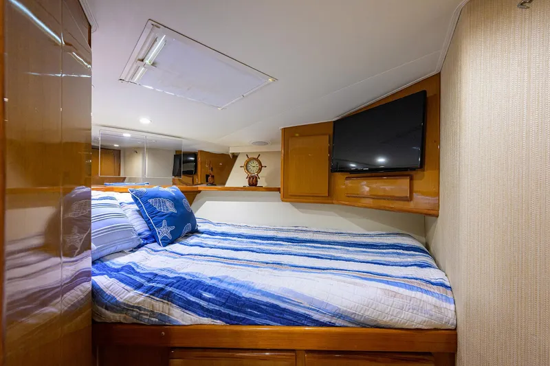 Slide: The Image of Cozy bedroom in 2000 Viking 50 Convertible yacht with striped bedding and wall-mounted TV. - 20