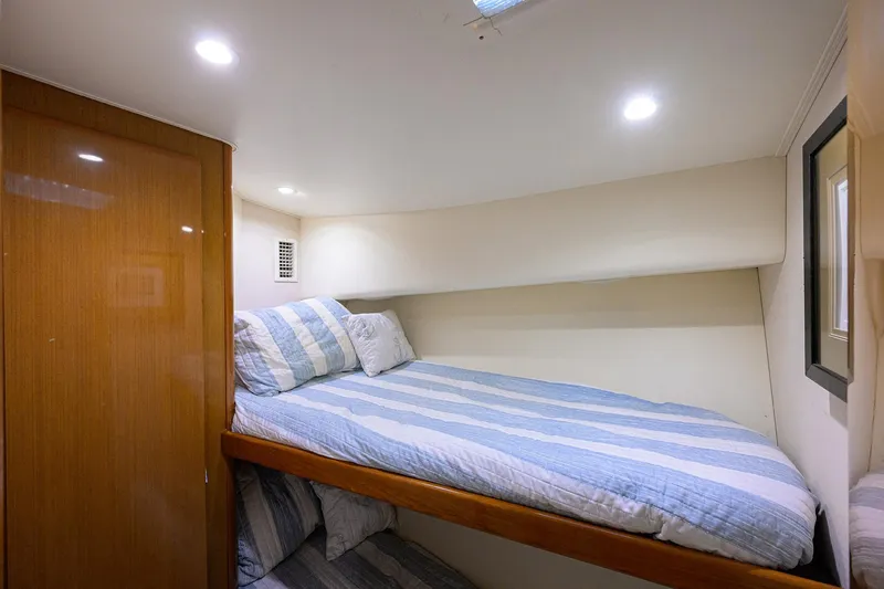 Slide: The Image of Cozy cabin interior of 2000 Viking 50 Convertible yacht with striped bedding. - 23