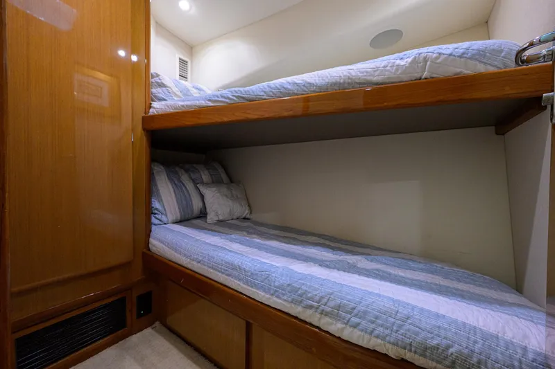 Slide: The Image of Bunk beds in 2000 Viking 50 Convertible yacht cabin, featuring wood paneling and cozy bedding. - 24
