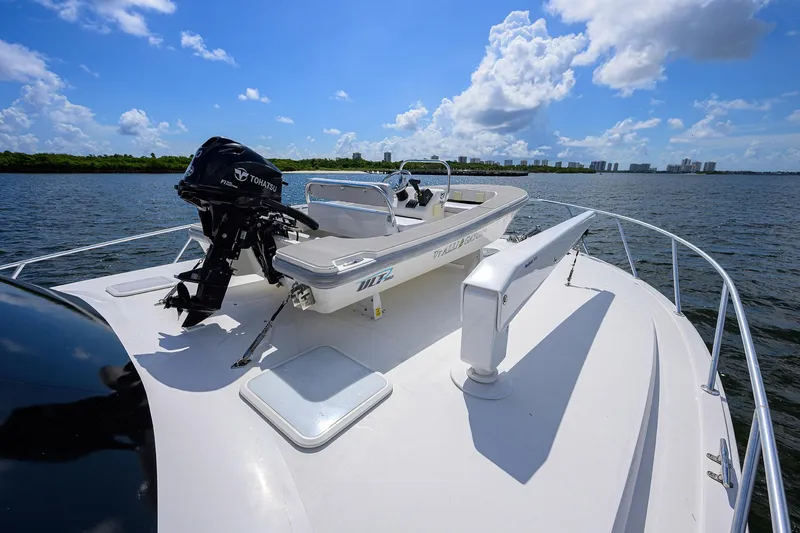 Slide: The Image of 2000 Viking 50 Convertible yacht with a small boat on deck, under a clear blue sky. - 31