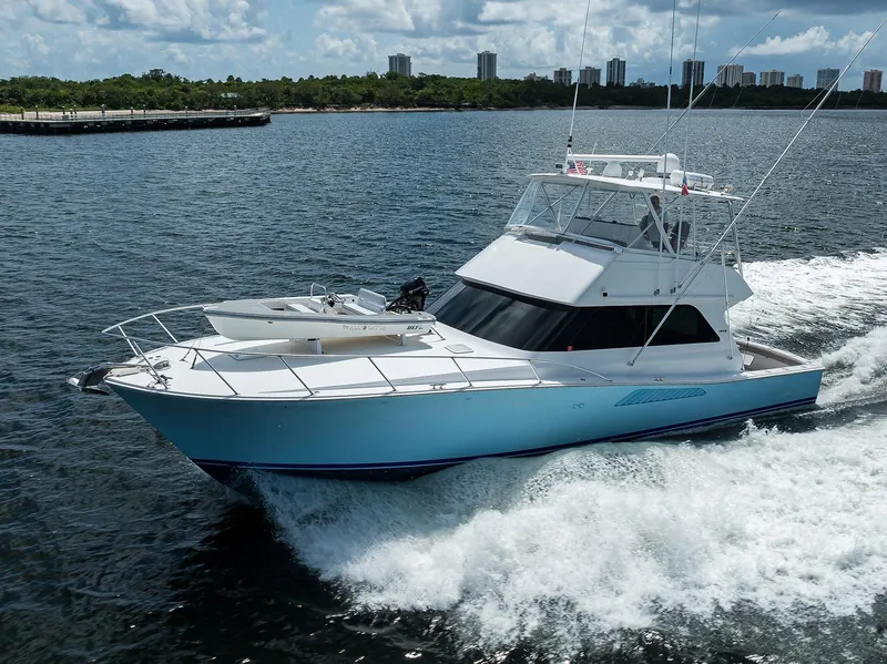 Slide: The Image of 2000 Viking 50 Convertible yacht cruising on open water, city skyline in background. - 4