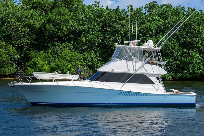 Slide: The Image of 2000 Viking 50 Convertible yacht on calm water, surrounded by lush greenery. - 5