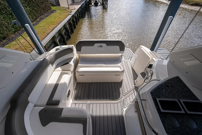 Slide: The Image of 2014 Monterey 295 Sport Yacht interior with seating, docked by a calm waterway. - 13