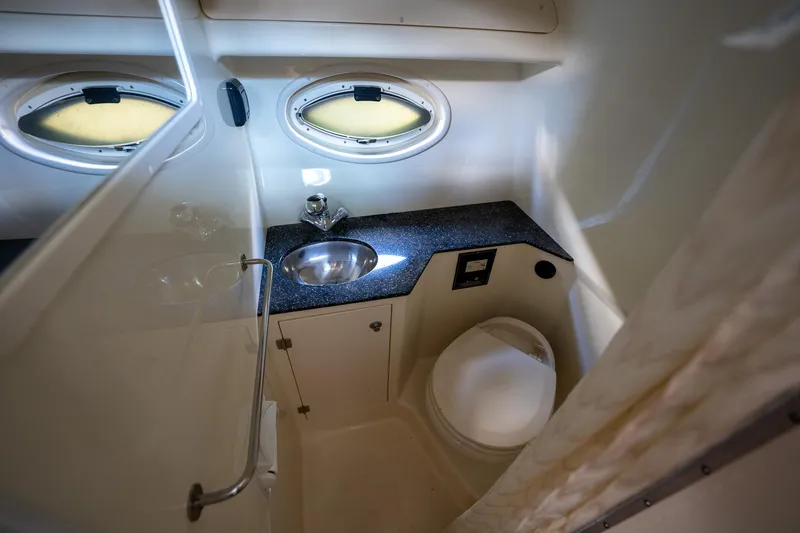 Slide: The Image of 2014 Monterey 295 Sport Yacht bathroom with sink, toilet, and porthole windows. - 29