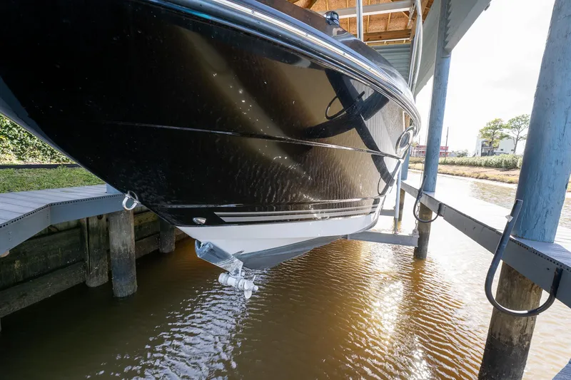 Slide: The Image of 2014 Monterey 295 Sport Yacht in dock, black hull, partially lifted above water. - 7
