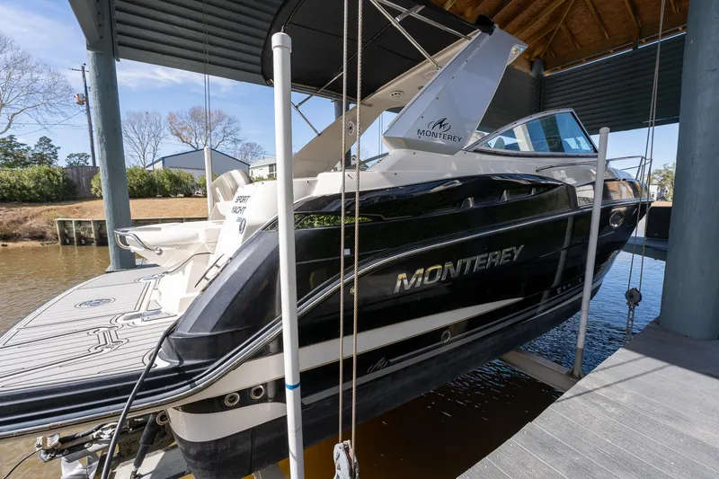 Slide: The Image of 2014 Monterey 295 Sport Yacht docked in a covered marina, showcasing sleek design and branding. - 9