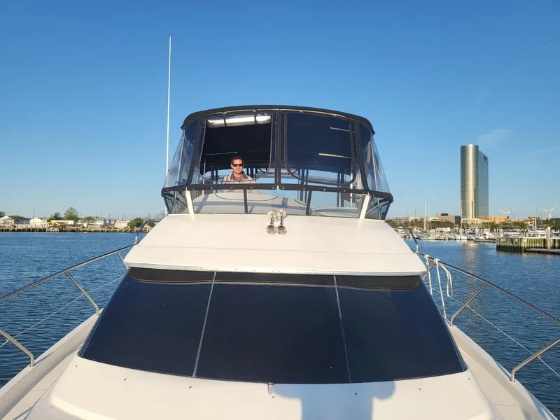 Slide: The Image of 2003 Silverton 410 Sport Bridge yacht on calm water with city skyline in background. - 10