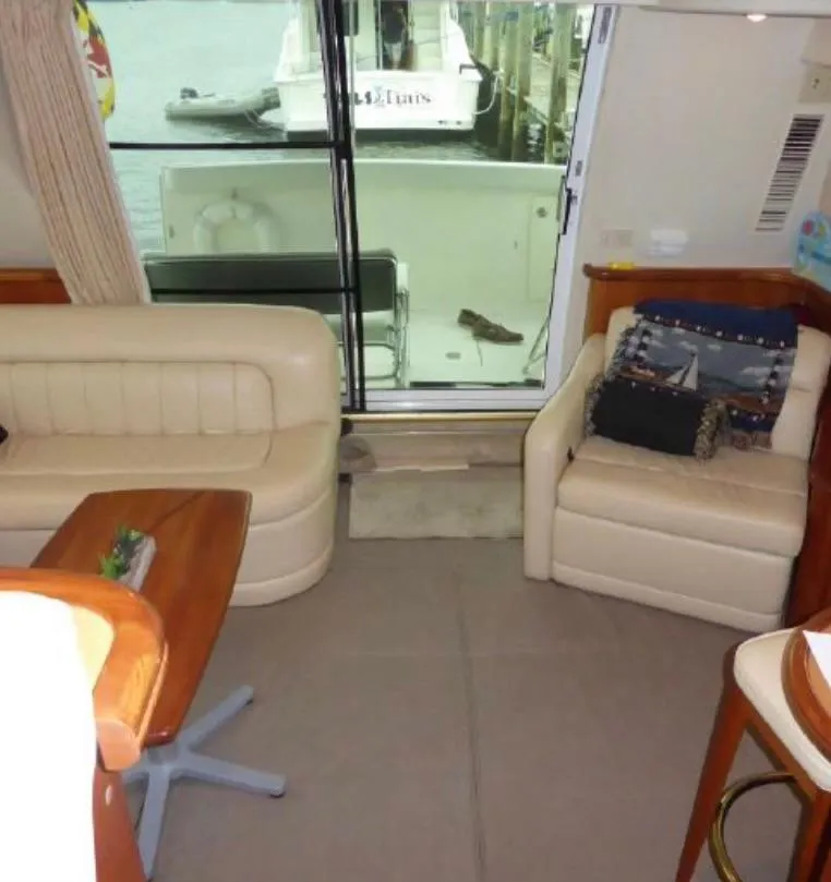 Slide: The Image of Interior of a 2003 Silverton 410 Sport Bridge yacht with beige seating and a view of the marina. - 9