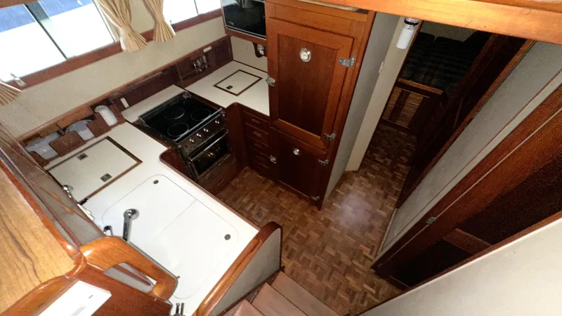 Slide: The Image of Interior of 1987 Grand Banks 46 Classic yacht, featuring a compact kitchen with wood cabinetry. - 30