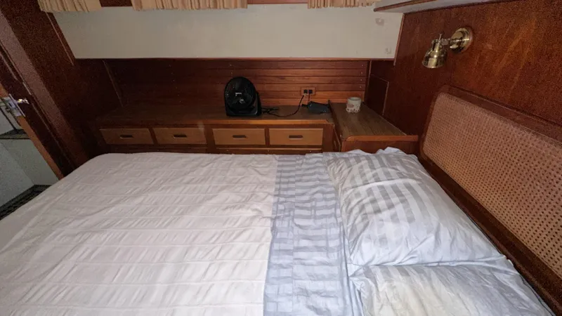 Slide: The Image of 1987 Grand Banks 46 Classic cabin interior with bed, wooden drawers, and wall lamp. - 34