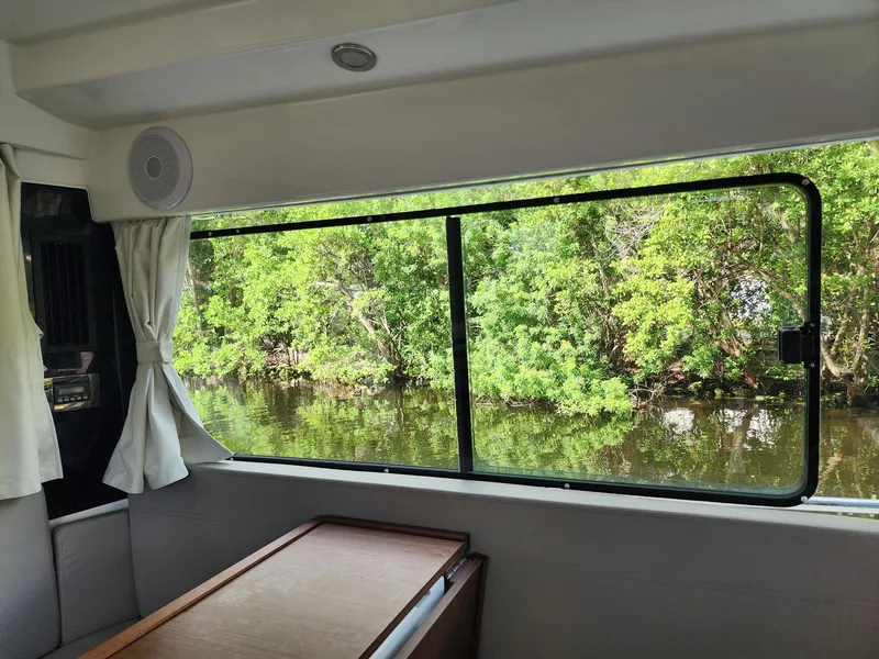 Slide: The Image of Interior view from 2023 Jeanneau NC Sport 895, showcasing large window and scenic waterway. - 11
