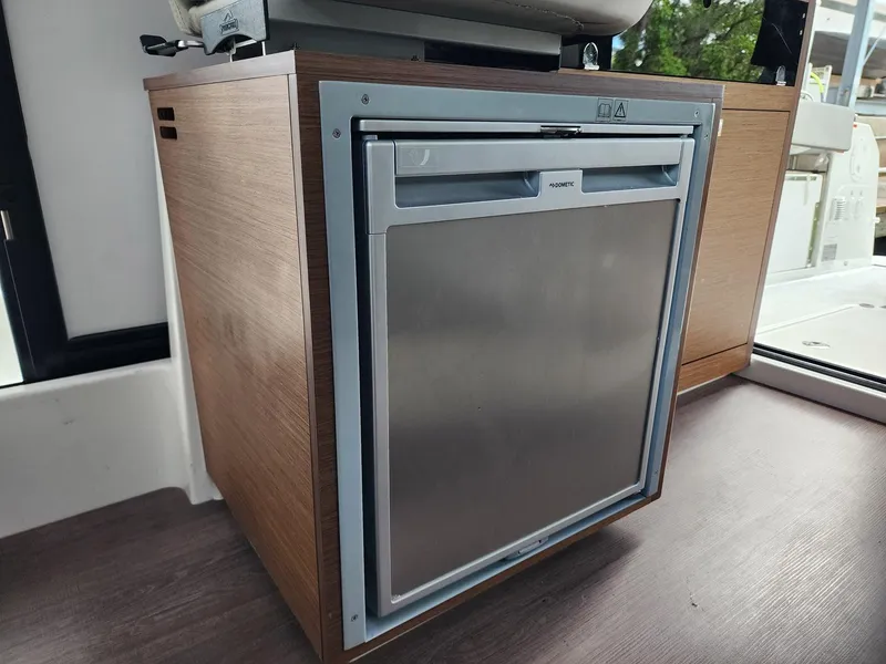 Slide: The Image of Compact fridge inside 2023 Jeanneau NC Sport 895 boat, featuring sleek wood cabinetry. - 17