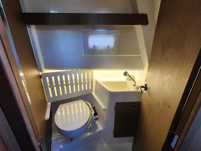 Slide: The Image of 2023 Jeanneau NC Sport 895 boat bathroom with toilet, sink, and modern lighting. - 23