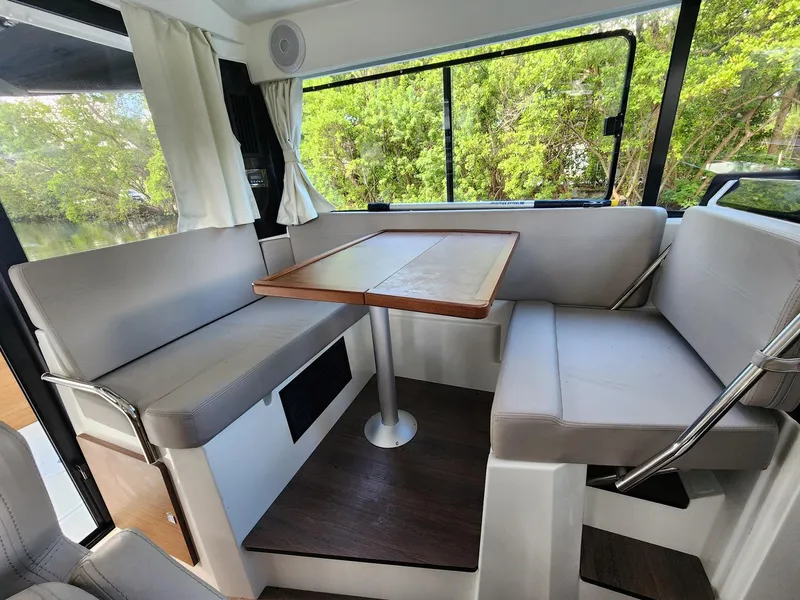 Slide: The Image of Interior of 2023 Jeanneau NC Sport 895, featuring a cozy dining area with cushioned seating. - 9