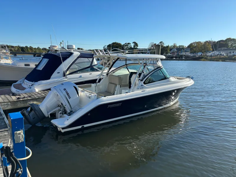 Slide: The Image of 2020 Pursuit DC 235 Dual Console boat docked on calm water. - 2