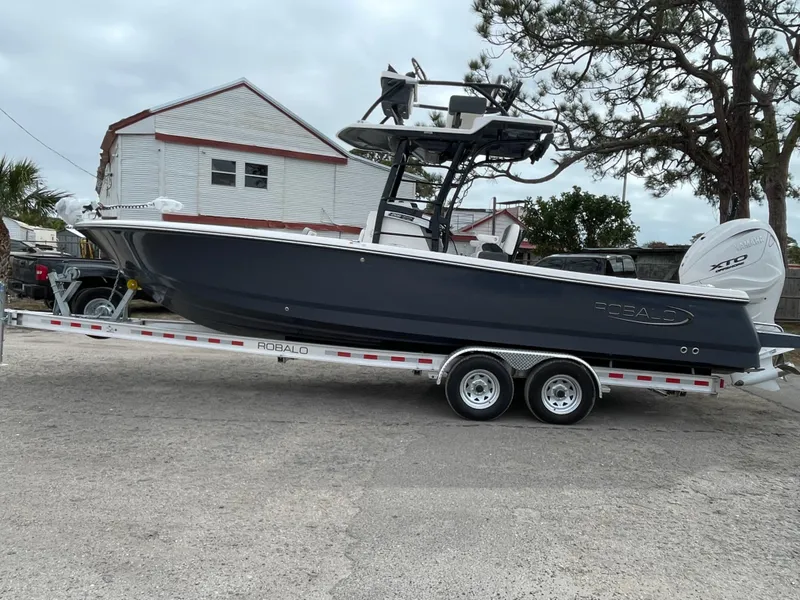 Slide: The Image of 2025 Robalo 266 Cayman SD boat on trailer, parked outdoors. - 2