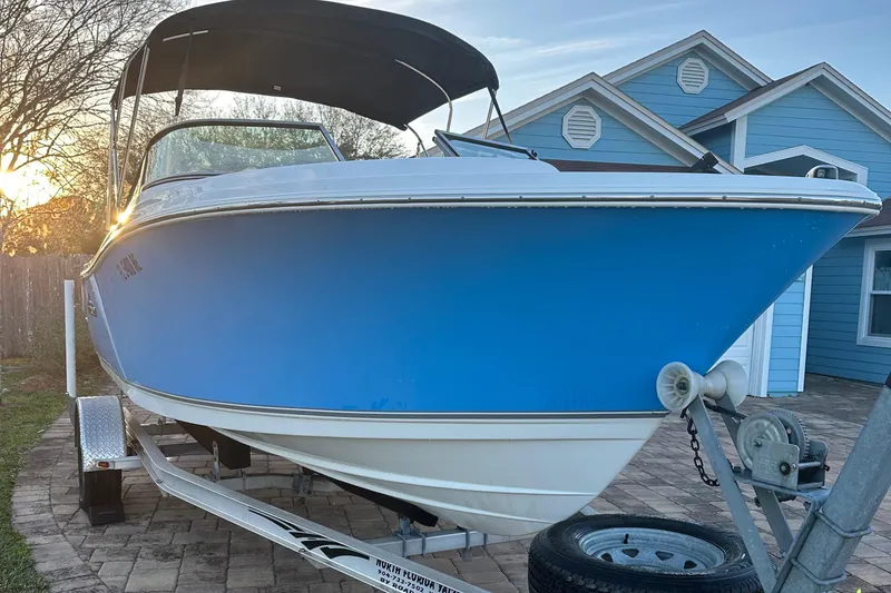 Slide: The Image of 2015 NauticStar 2000 XSDC boat on trailer, blue hull, parked near house. - 18