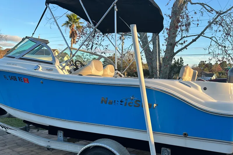 Slide: The Image of 2015 NauticStar 2000 XSDC boat with blue hull and canopy on trailer. - 22