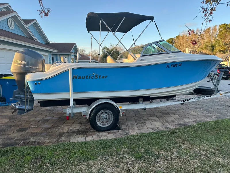Slide: The Image of 2015 NauticStar 2000 XSDC boat on trailer, blue hull, parked in residential driveway. - 8