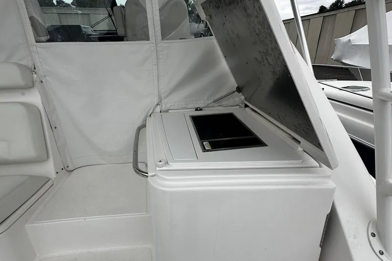 Slide: The Image of 2023 Tiara Yachts 43 Open interior with open storage compartment, white seating, and sleek design. - 23