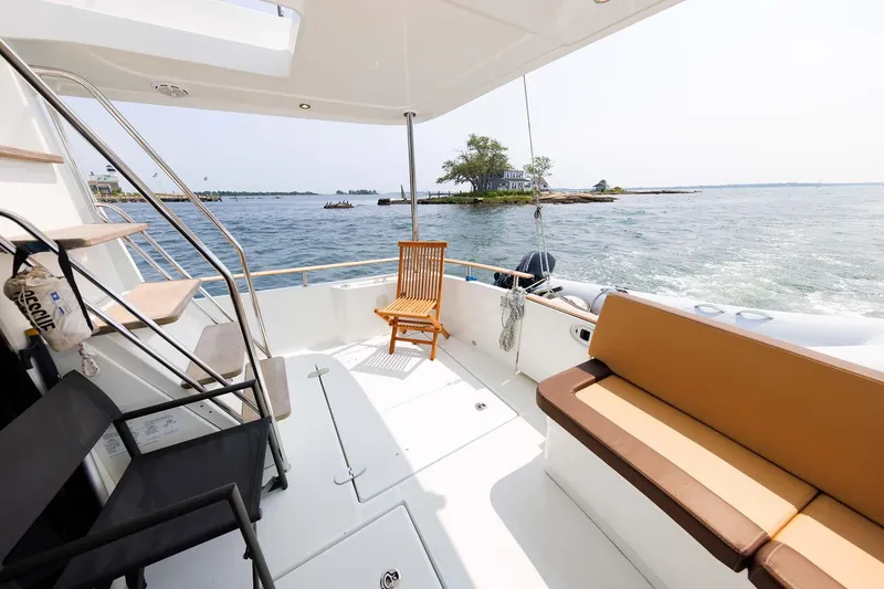 Slide: The Image of 2016 Beneteau Swift Trawler 44 deck with seating, overlooking serene waters and distant islands. - 44