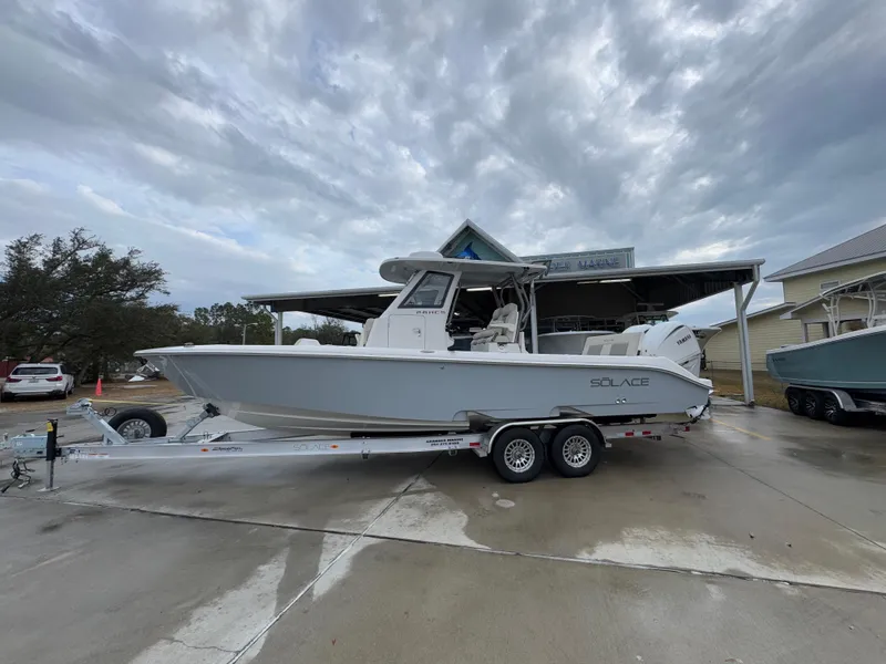 The Image of 2025 Solace 28 HCS boat on trailer, parked outdoors under cloudy sky. - 1