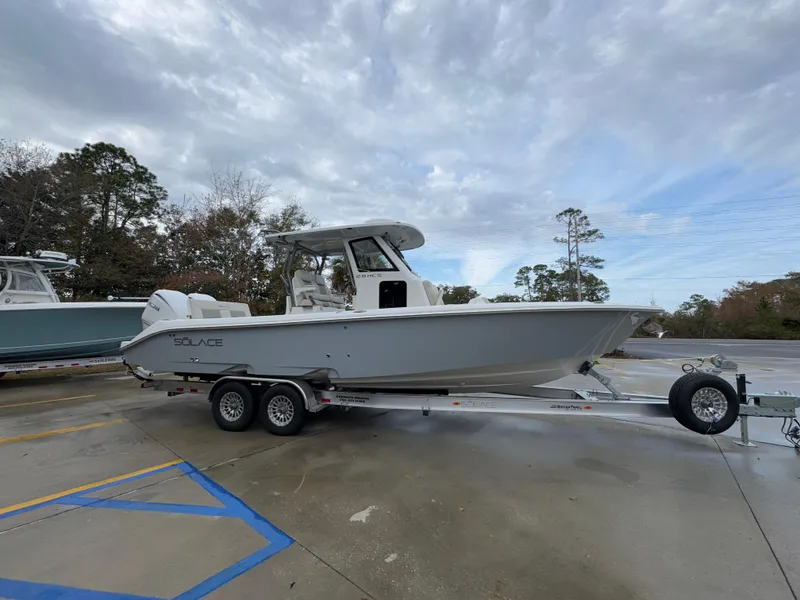 Slide: The Image of 2025 Solace 28 HCS boat on trailer, parked outdoors under cloudy sky. - 11