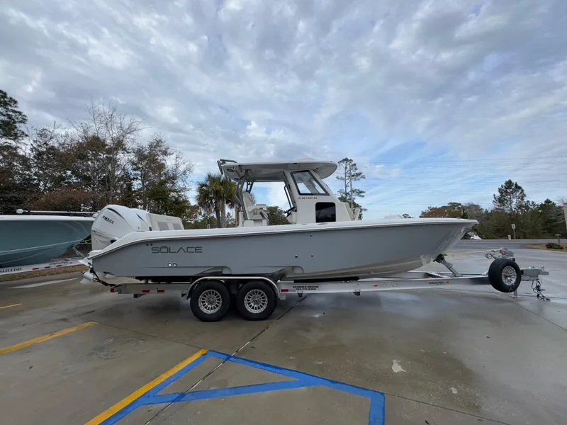 Slide: The Image of 2025 Solace 28 HCS boat on trailer, parked outdoors under cloudy sky. - 12