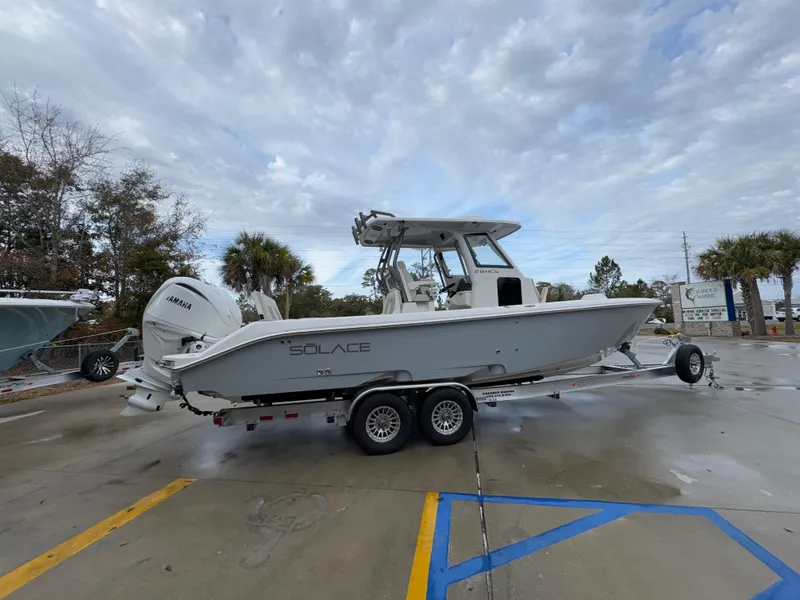 Slide: The Image of 2025 Solace 28 HCS boat on trailer, parked outdoors under cloudy sky. - 13