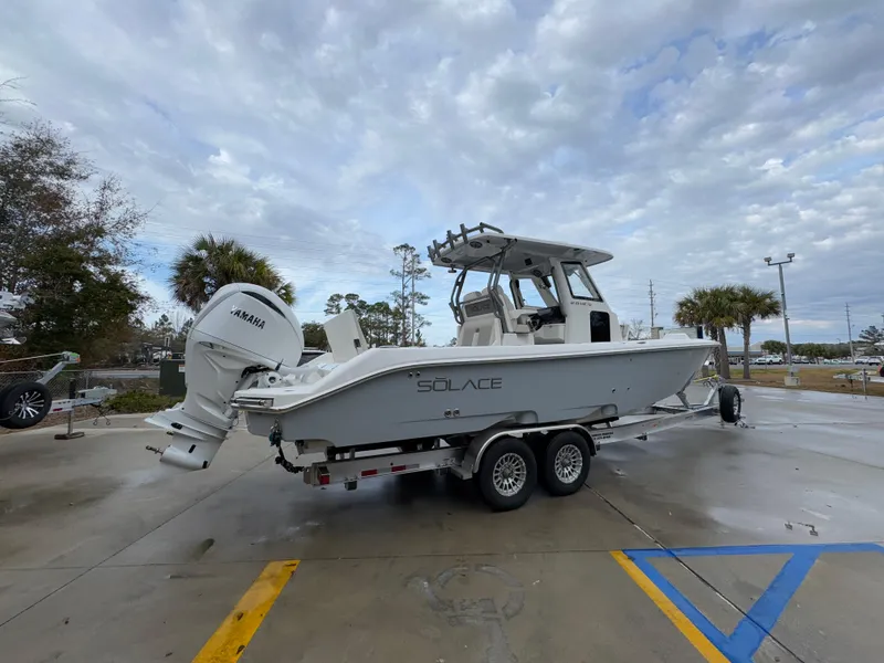 Slide: The Image of 2025 Solace 28 HCS boat on trailer, parked outdoors under cloudy sky. - 14