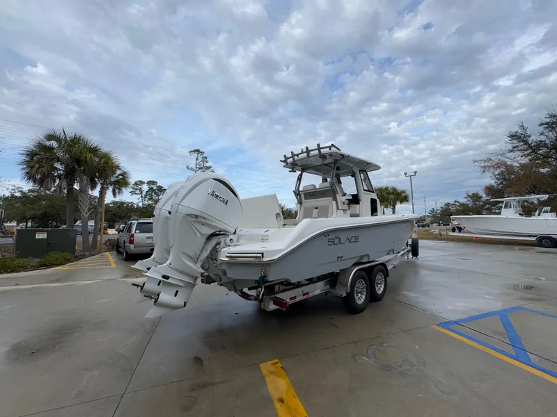 Slide: The Image of 2025 Solace 28 HCS boat on trailer in parking lot under cloudy sky. - 15