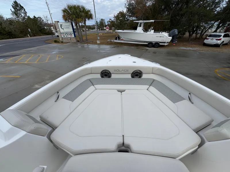 Slide: The Image of 2025 Solace 28 HCS boat interior with cushioned seating and speakers, parked outdoors. - 22