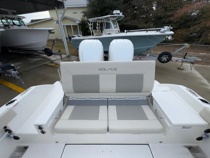 Slide: The Image of 2025 Solace 28 HCS boat with cushioned seating and dual engines in a marina setting. - 43