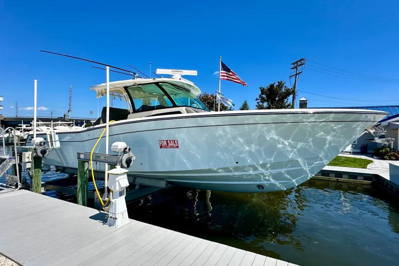 The Image of 2025 Grady-White Canyon 386 boat for sale, docked with American flag, clear blue sky. - 0