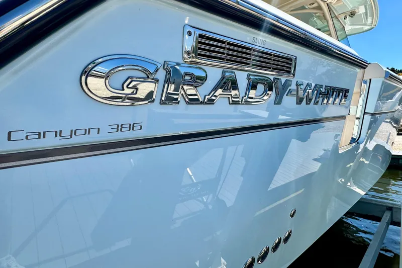 Slide: The Image of 2025 Grady-White Canyon 386 boat, sleek design with chrome branding, docked in sunlight. - 3