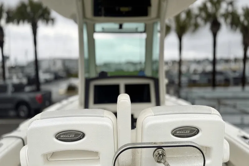 Slide: The Image of 2015 Boston Whaler 280 Outrage boat seats with logo, marina background. - 11
