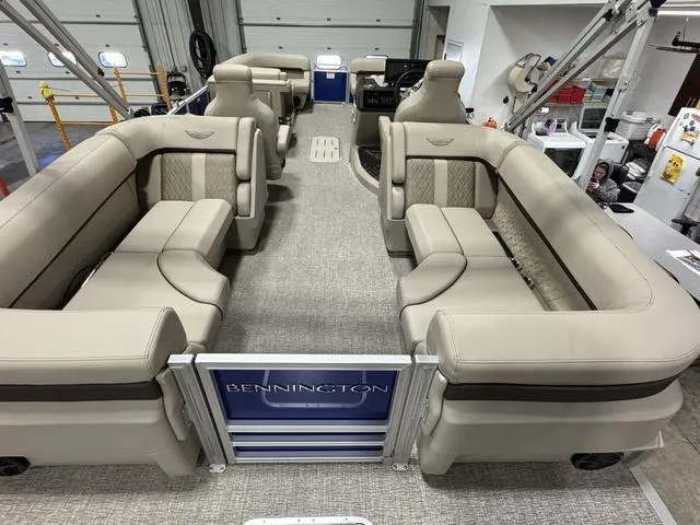 Slide: The Image of 2025 Bennington M Quad Bench 24 MFB pontoon boat with luxurious beige seating and spacious interior. - 12