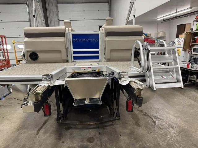 Slide: The Image of 2025 Bennington M Quad Bench 24 MFB pontoon boat in a garage, rear view with ladder. - 20