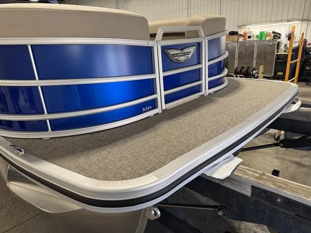 Slide: The Image of 2025 Bennington M Quad Bench 24 MFB pontoon boat with blue paneling in a workshop. - 22