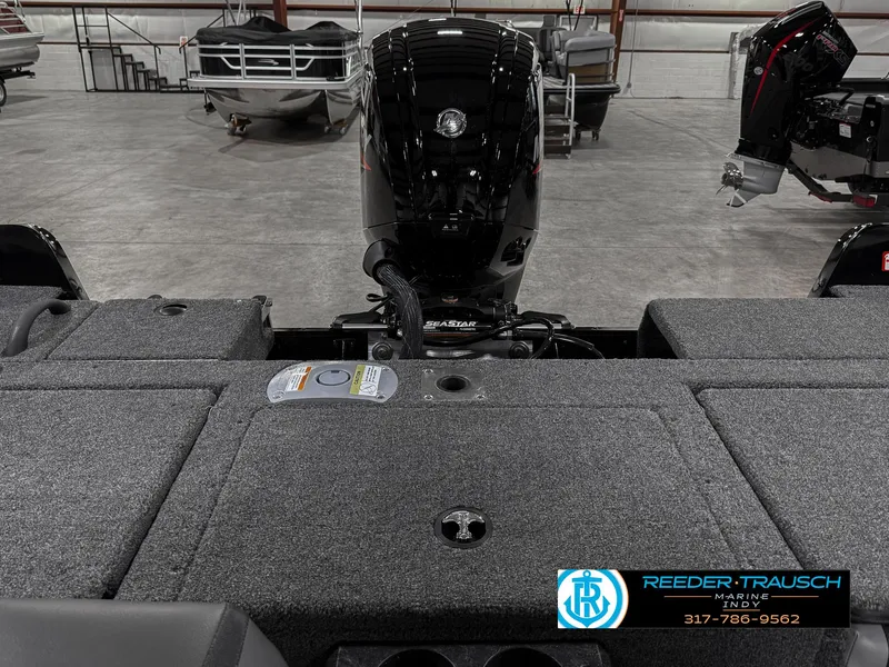 Slide: The Image of 2025 Lund 1775 IMPACT XS SINGLE boat interior with motor, displayed in a showroom. - 19