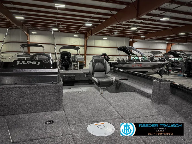 Slide: The Image of 2025 Lund 1775 IMPACT XS SINGLE boat interior in showroom, featuring seating and storage. - 24