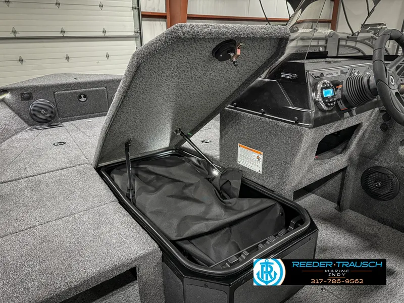 Slide: The Image of 2025 Lund 1775 IMPACT XS boat interior with open storage compartment and dashboard view. - 29