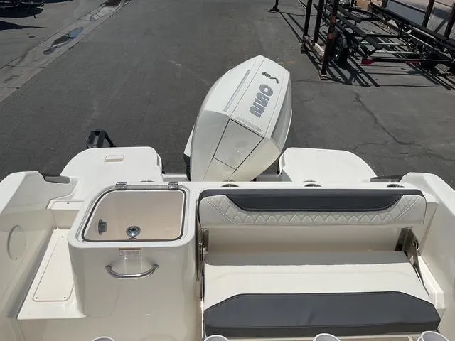 Slide: The Image of 2025 Bayliner Trophy T24CC boat with seating and outboard motor, docked on pavement. - 10