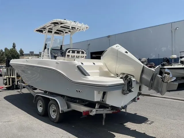 Slide: The Image of 2025 Bayliner Trophy T24CC boat on trailer, parked outdoors, showcasing sleek design and powerful engine. - 3